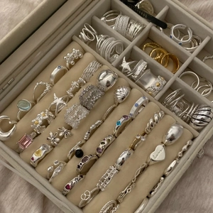 Assorted vintage silver and gold plated rings with gemstones in a beige jewelry box