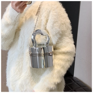 Silver cylindrical acrylic clutch bag with metal chain strap and unique handle on model