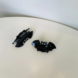 Pair of black bat hair claws with glitter finish and cute cartoon eyes for Halloween