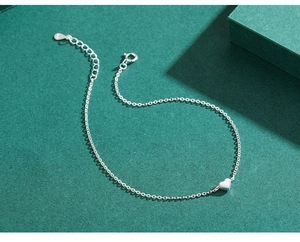 Macro shot of S925 sterling silver heart charm bracelet with adjustable cross chain
