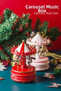 Close-up of pink and red wooden carousel music boxes with festive Christmas decorations