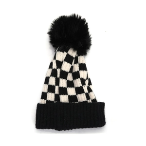 Détail du bonnet en tricot à damier avec pompon en fausse fourrure noire et revers