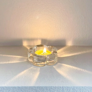 Floral clear glass candle holder casting radial light patterns on white tabletop