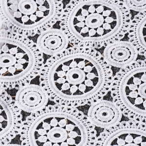Dettaglio del tessuto in pizzo bianco all'uncinetto con intricati motivi floreali