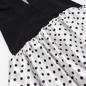 Detail of white satin dress with black polka dots featuring pleated texture and smooth finish