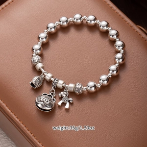 Detail of vintage silver beaded bracelet with fortune bell, pony and lotus pendants