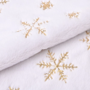 Detailed texture of white faux fur Christmas tree skirt with golden sequin snowflakes