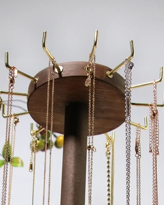 Detail of wooden jewelry stand featuring multiple gold metal hooks for necklace display