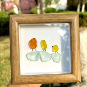 Main tenant un cadre en bois d'art en verre de mer avec trois petits oiseaux