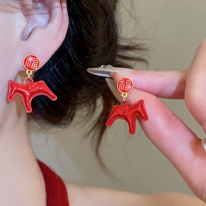 Detail of a red enamel horse charm earring with Fú character stud on a model