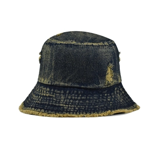 Detailed view of distressed dark denim bucket hat with frayed edges and ripped textures