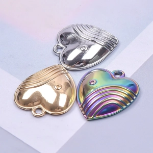 Three heart pendants in gold, silver, and rainbow steel with embossed detailing