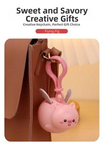 Pink silicone flying pig keychain with wings used as a charm on a brown leather bag