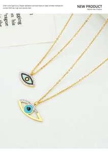 Detail of two gold titanium steel necklaces featuring blue evil eye pendants on white fabric