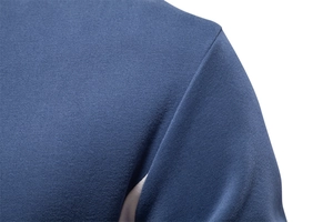 Macro detail of blue knitted cotton fabric showing precise shoulder stitching and texture