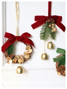 Close-up of Christmas wreath with velvet bows, pine cones and gold bells on white background