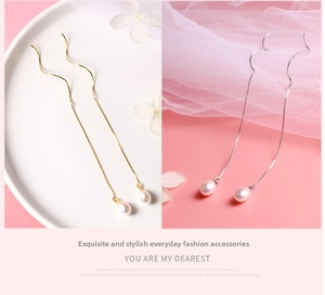 Macro detail of long wavy S925 silver threader earrings with natural freshwater pearls