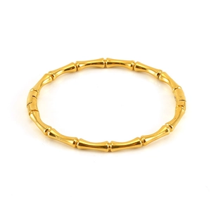 Dettaglio di un bracciale in acciaio dorato a forma di bambù con maglie lucide e chiusura