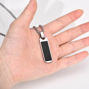 Macro shot of rectangular silver pendant with black onyx inlay held in a hand