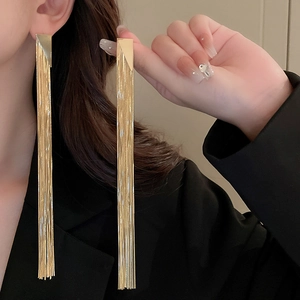 Elegant geometric gold tassel earrings with hanging chains on a model with black suit