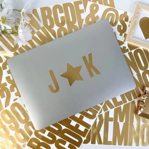 Close-up of gold vinyl letter stickers applied to a sleek silver laptop surface