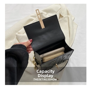 Interior capacity of black embossed leather bag with gold chain and metal buckle detail