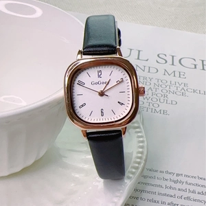 Detail of vintage square rose gold watch with black leather strap on a ceramic tray