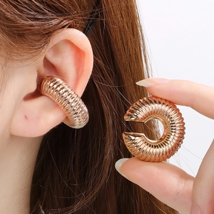 Macro detail of rose gold caterpillar ear cuff showing spiral ribbed texture on model