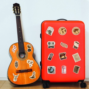 Retro decorative stickers with map and gramophone motifs on a guitar and red suitcase