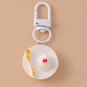 Detailed macro view of a miniature food keychain with a white ceramic plate and gold spoon