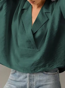 Detailed view of dark green satin short sleeve shirt with V-neck and silky texture