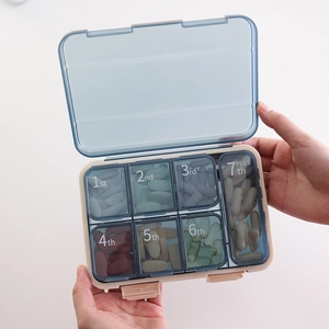 Portable 7-compartment pill organizer with translucent lids and white capsules in hand