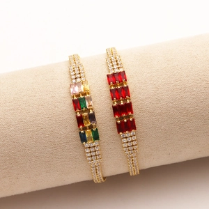 Macro di bracciali dorati con zirconi quadrati colorati su un espositore per gioielli