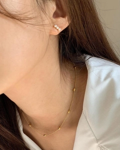 Nahaufnahme der eleganten Goldperlenkette und Dreifach-Perlenohrstecker an einem Modell