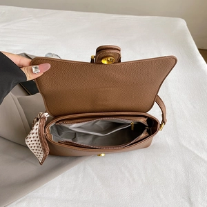 Brown vintage leather shoulder bag with gold hardware and polka dot scarf accessory