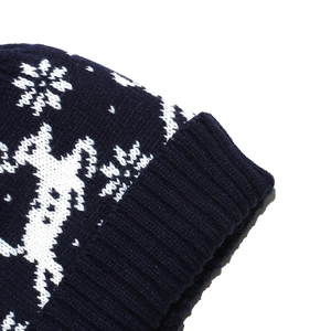 Détail du bonnet en tricot bleu marine avec motifs jacquard de renne et flocons de neige