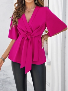 Détail du haut femme rose fuchsia à col en V avec nœud élégant à la taille et tissu doux