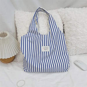 Détail du sac cabas en toile à rayures bleues et blanches avec étiquette en tissu chic