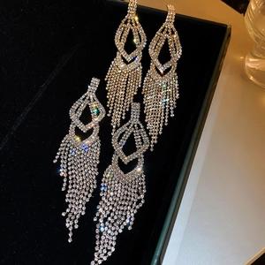 Close-up of sparkling long tassel earrings with pavé rhinestones on black velvet