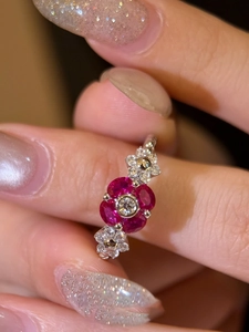 Macro shot of silver floral ring featuring ruby red stones and center white zircon