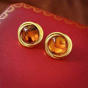 Detail of amber resin stud earrings with vintage gold metal layers on red jewelry box