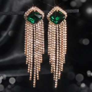 Detail of luxury long tassel earrings with green square stone and white crystals