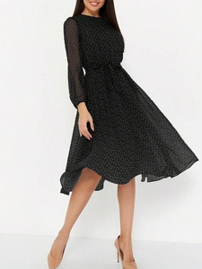 Détail d'une robe longue en mousseline noire à pois blancs avec manches longues et ceinture