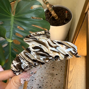 Detail of large acetate hair claw clip featuring black and white marble ink patterns