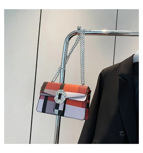 Detail of checkered shoulder bag with oversized crystal buckle and silver chain strap