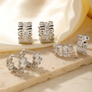 Three silver-toned zircon hoop earrings artfully displayed on natural stone with satin