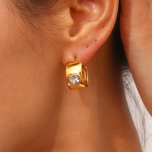 Macro shot of gold-plated chunky C-hoop earring with embedded heart-shaped zircon stone