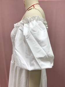 Detail of white off-the-shoulder floral dress featuring smocking and puff sleeves