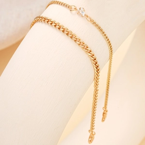 Detail of double-layer gold anklet featuring a clear heart-shaped zircon pendant
