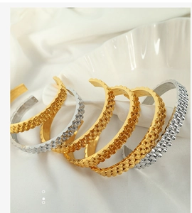 Detailed view of gold and silver watchband-style textured titanium steel open bangles